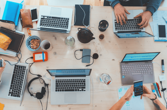A group of individuals collaborating at a table, each using laptops, focused on integrating newsletter software with marketing platforms.